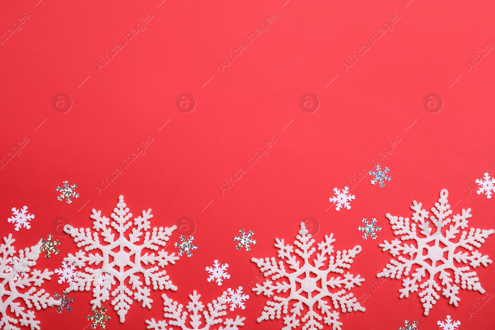 Photo of Beautiful decorative snowflakes on red background, flat lay. Space for text