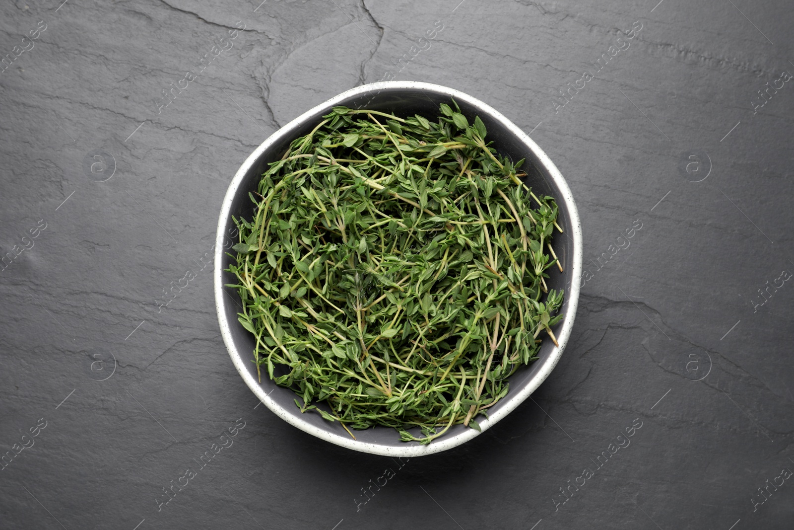 Photo of Aromatic thyme in bowl on black table, top view