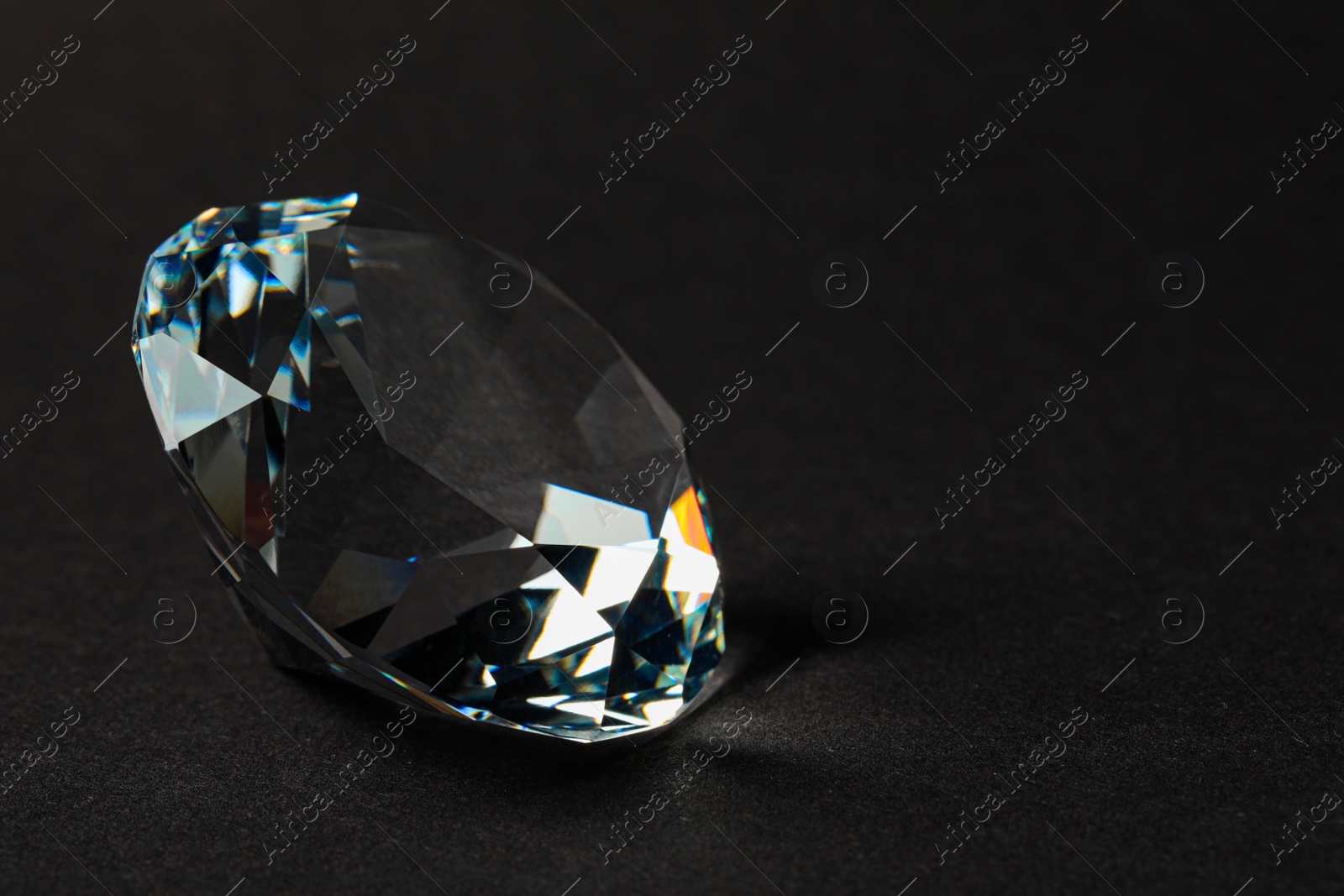 Photo of Beautiful dazzling diamond on dark background, closeup. Space for text