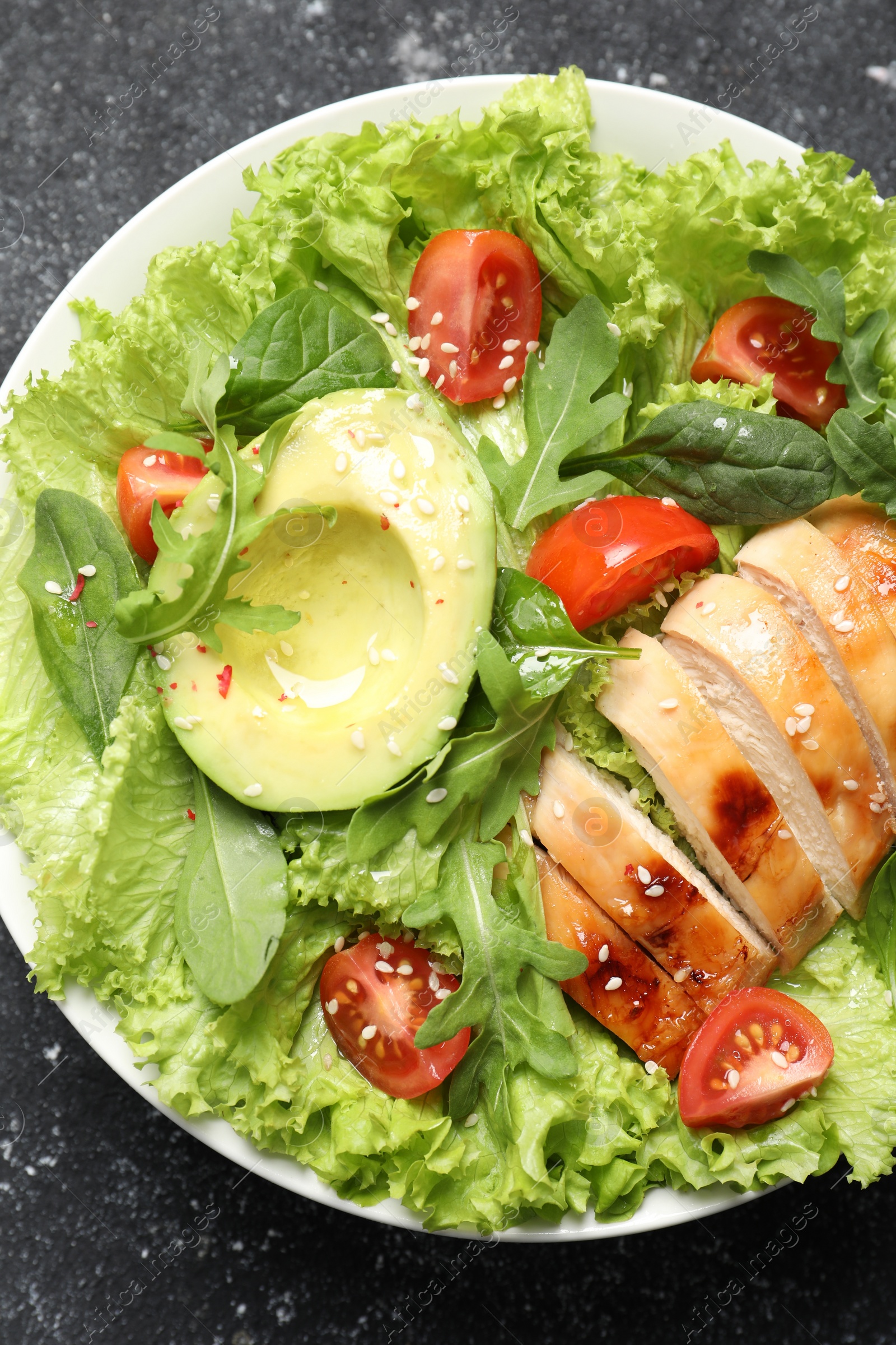 Photo of Delicious salad with chicken, cherry tomato and avocado on grey textured table, top view
