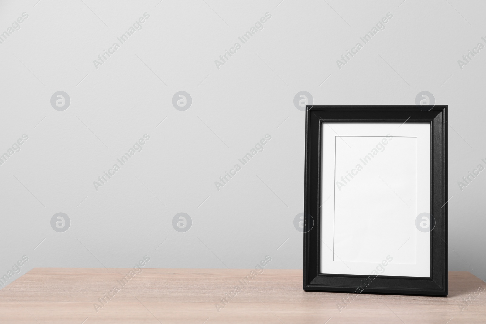 Photo of Empty square frame on wooden table, space for text