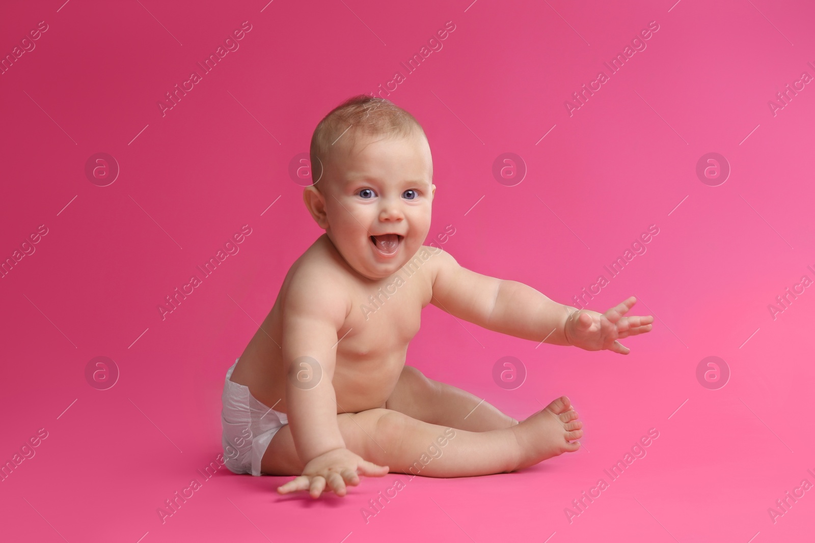 Photo of Cute baby in dry soft diaper sitting on pink background