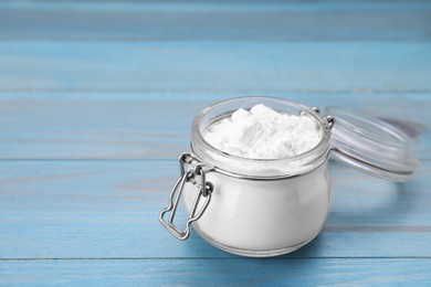 Photo of Glass jar of natural starch on light blue wooden table, closeup. Space for text