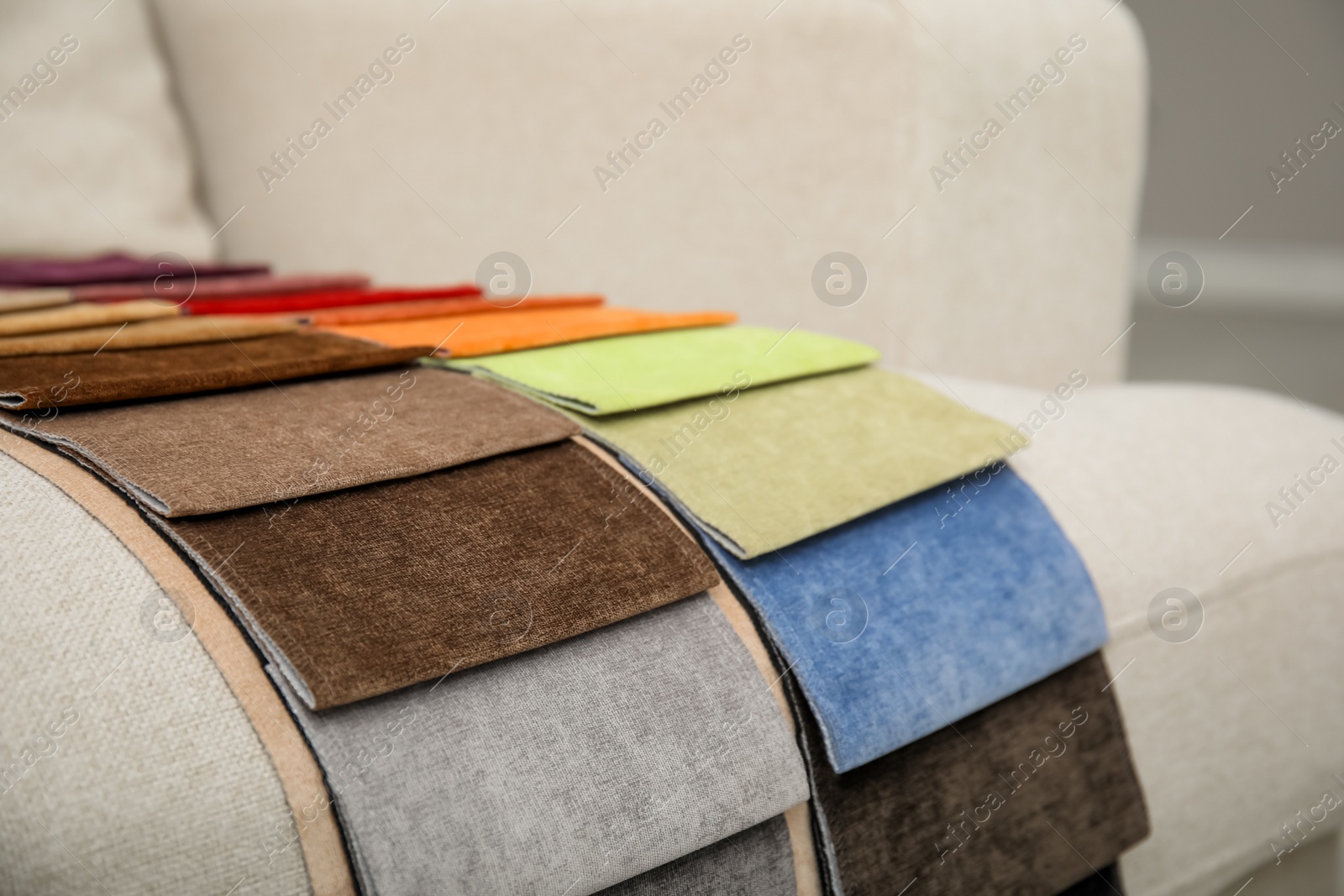 Photo of Catalog of colorful fabric samples on beige sofa, closeup