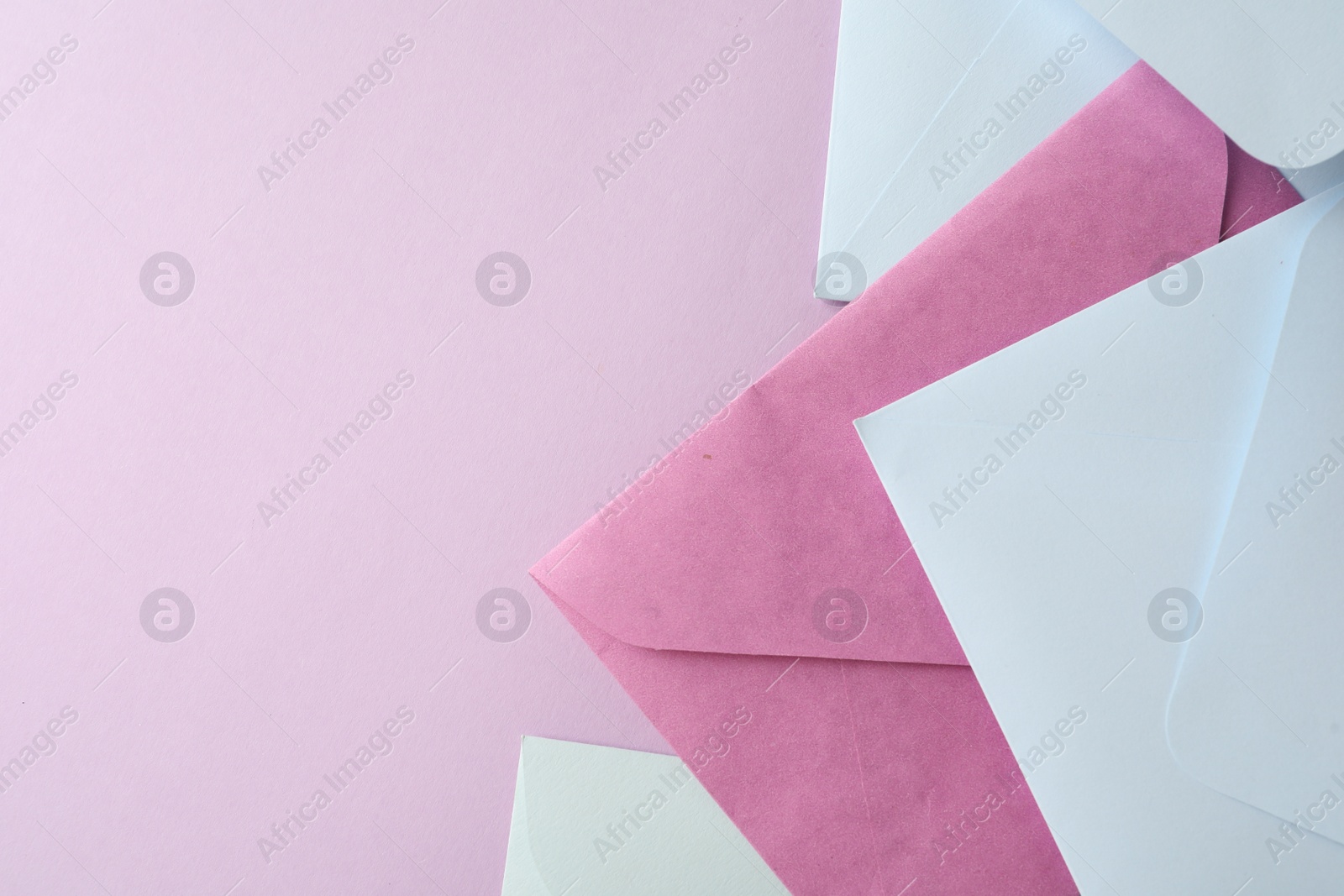 Photo of Colorful paper envelopes on pink background, flat lay. Space for text