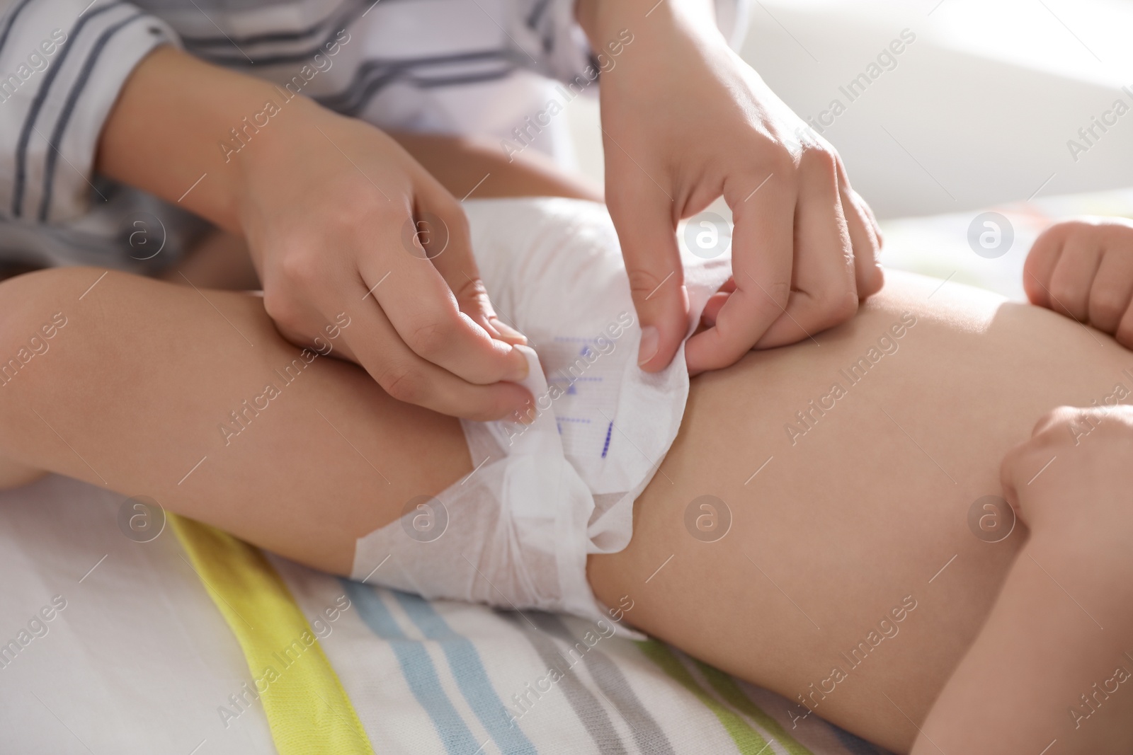 Photo of Mother changing baby's diaper on table at home, closeup