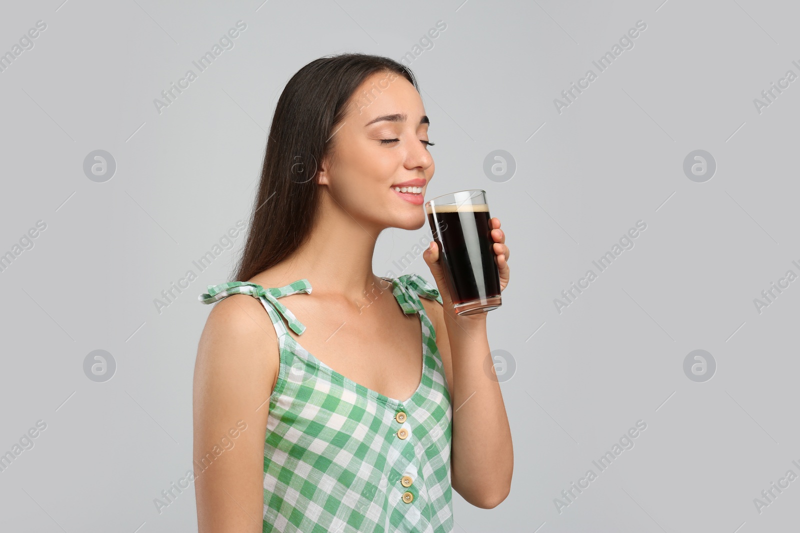 Photo of Beautiful woman with cold kvass on light grey background. Traditional Russian summer drink