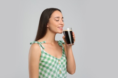 Photo of Beautiful woman with cold kvass on light grey background. Traditional Russian summer drink