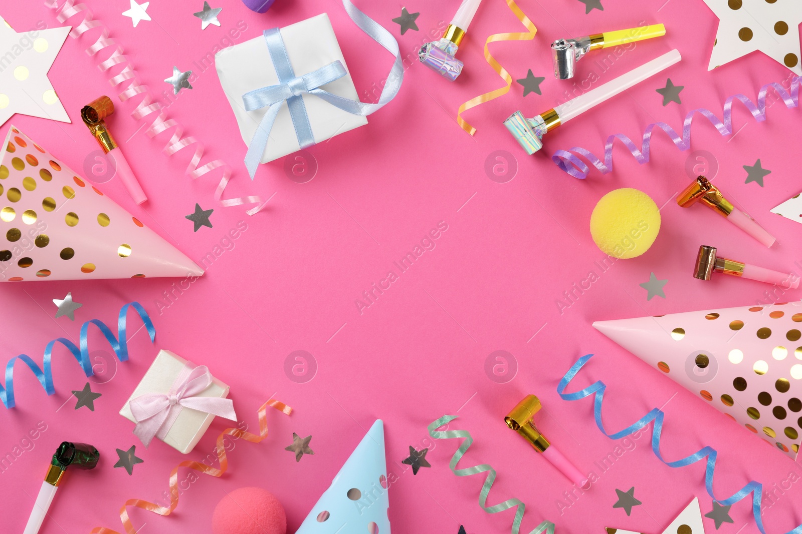 Photo of Frame of colorful serpentine streamers and other party accessories on pink background, flat lay. Space for text