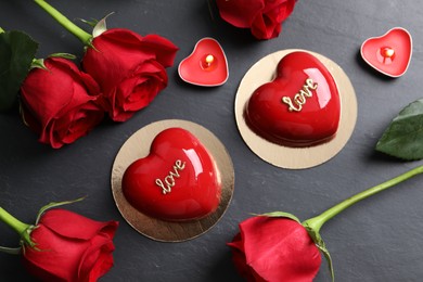 Photo of St. Valentine's Day. Delicious heart shaped cakes, roses and candles on black table, flat lay