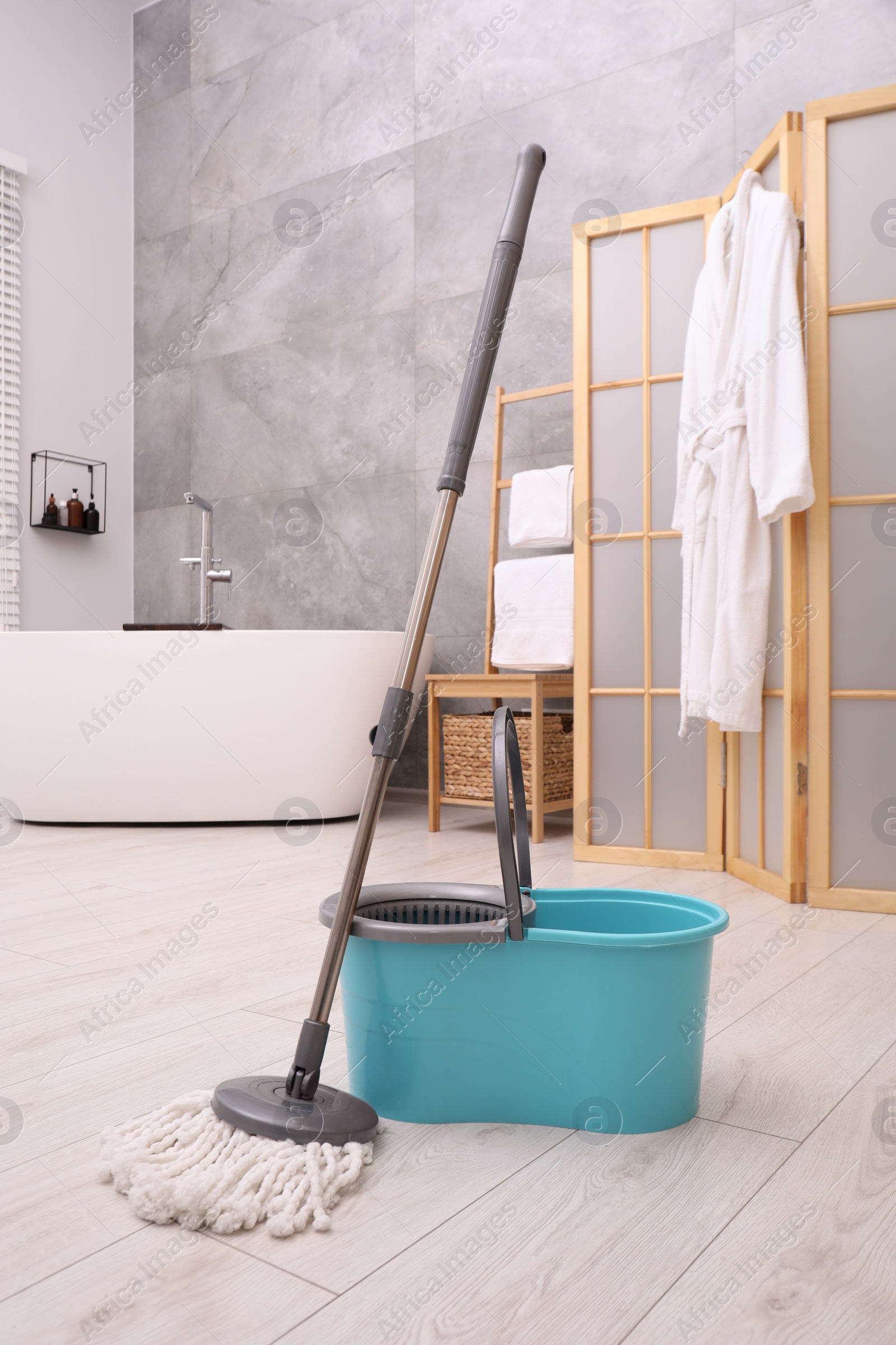 Photo of Mop and plastic bucket in bathroom. Cleaning floor