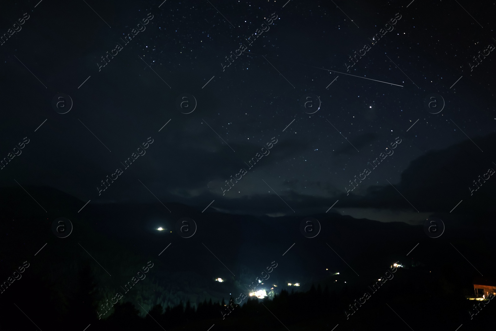 Image of Picturesque view of small town in mountains and beautiful starry sky at night