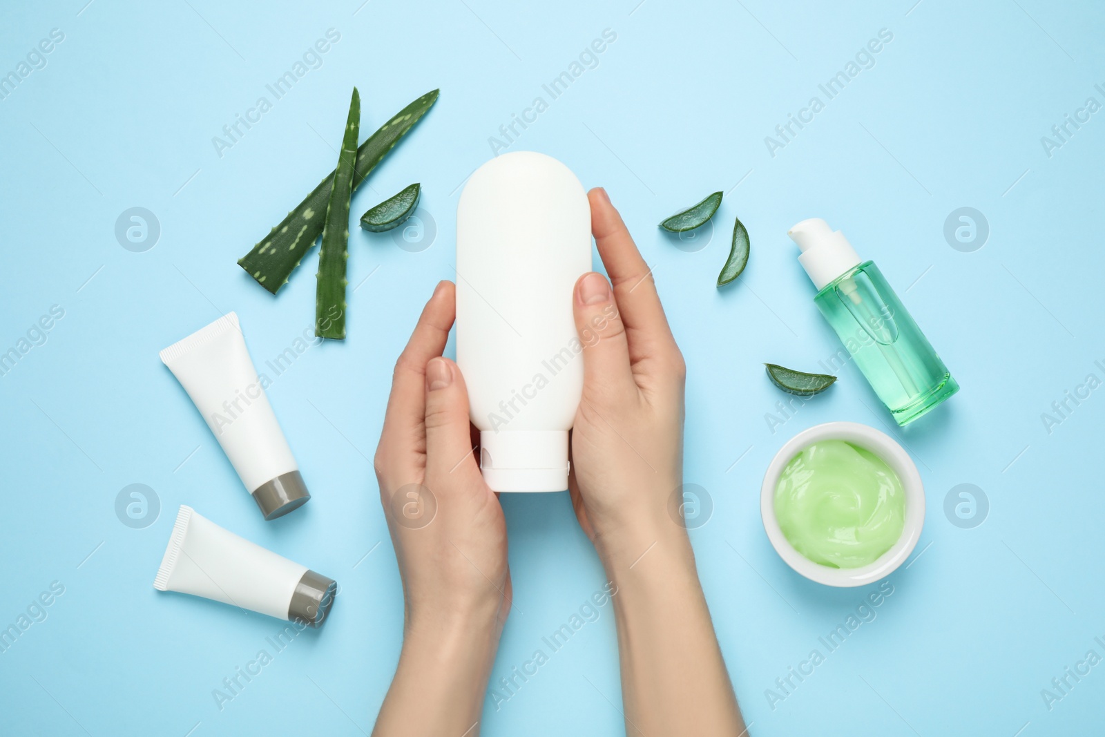 Photo of Woman with different cosmetic products and aloe on light blue background, flat lay