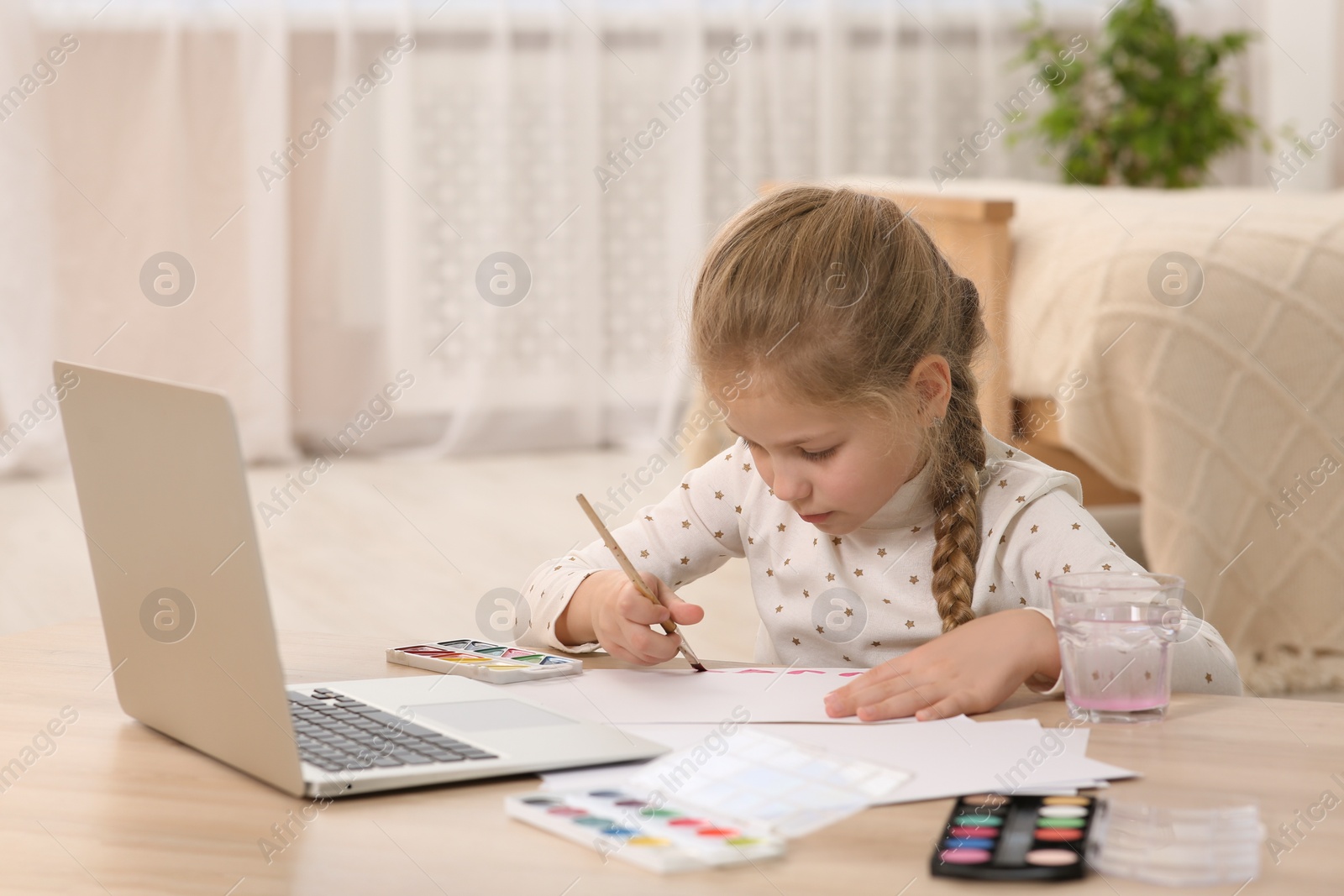 Photo of Little girl learning to paint with online course at home. Space for text