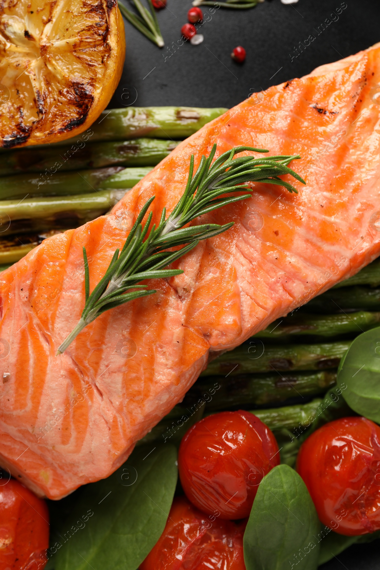 Photo of Tasty grilled salmon with tomatoes, asparagus and spices on plate, top view