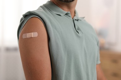 Man with sticking plaster on arm after vaccination at home, closeup