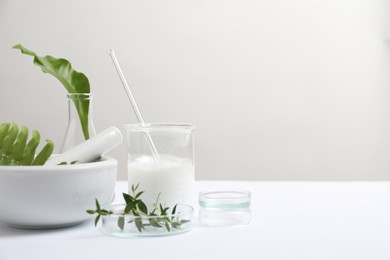 Organic cosmetic product, natural ingredients and laboratory glassware on white table, space for text
