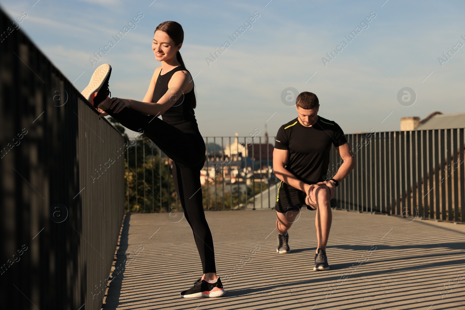 Photo of Attractive couple doing sports exercises near fence outdoors