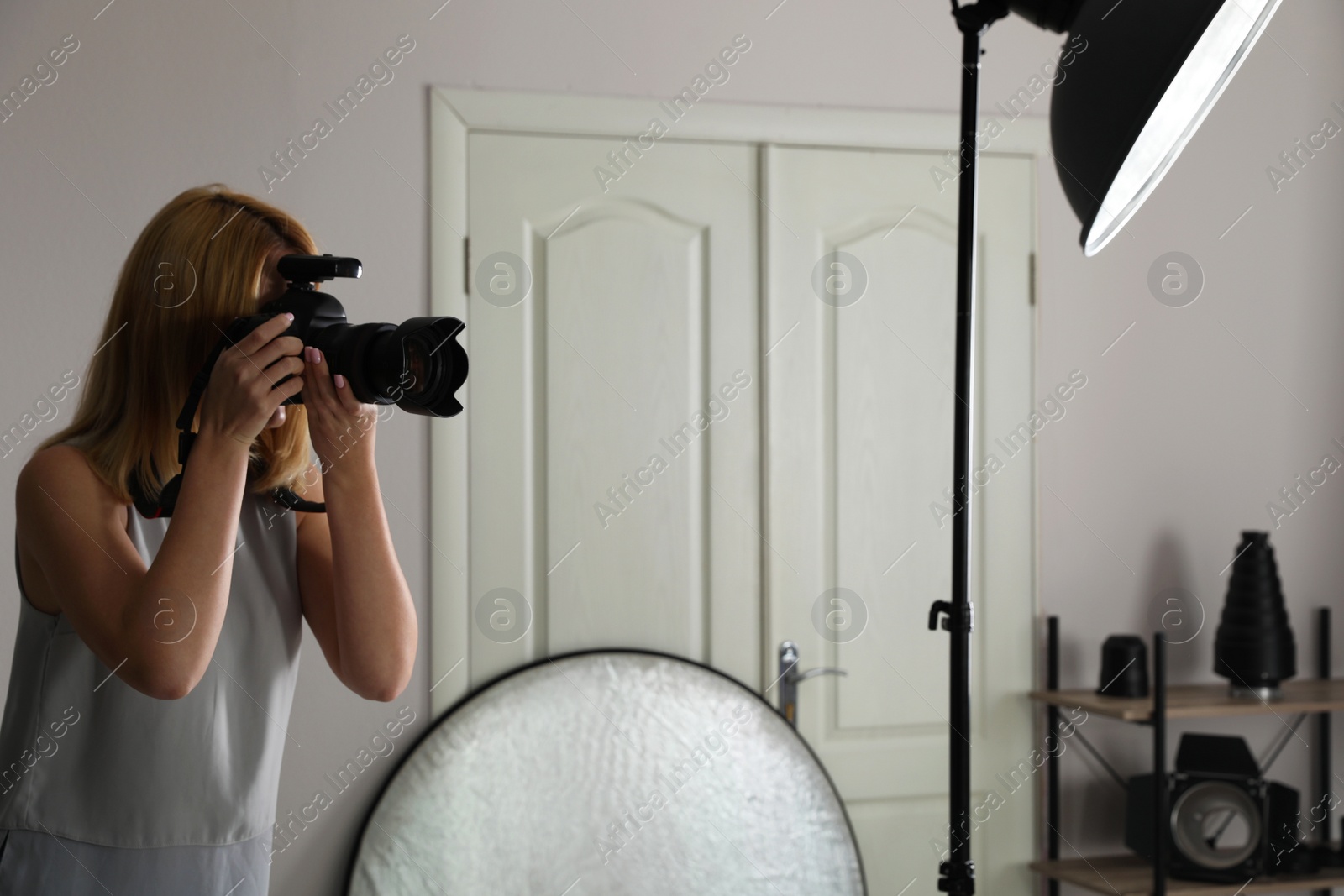 Photo of Young woman with professional camera in photo studio
