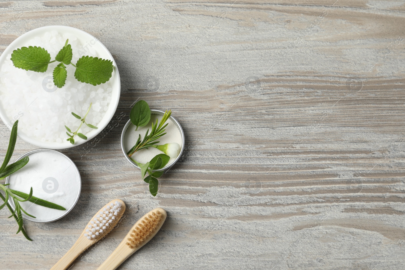 Photo of Toothbrushes, green herbs and other teeth care products on wooden table, flat lay. Space for text