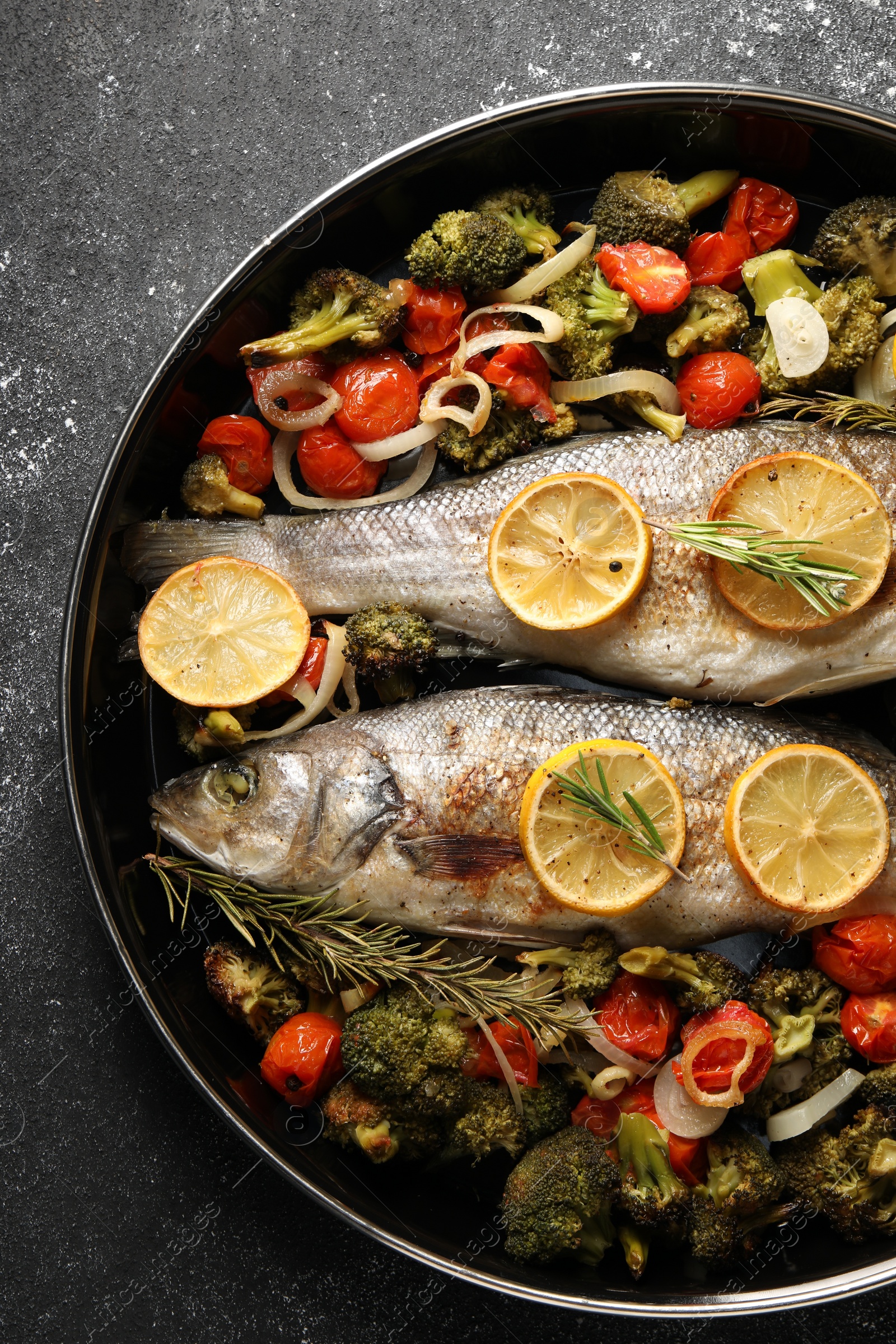 Photo of Baked fish with vegetables, rosemary and lemon on black textured table, top view