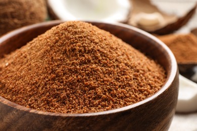 Photo of Natural coconut sugar in wooden bowl on table, closeup