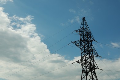 Photo of Telephone pole and wires against blue sky with clouds