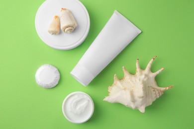 Different cosmetic products and seashells on light green background, flat lay