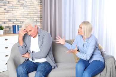Photo of Mature couple arguing in living room. Relationship problems