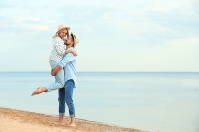 Photo of Happy romantic couple spending time together on beach, space for text