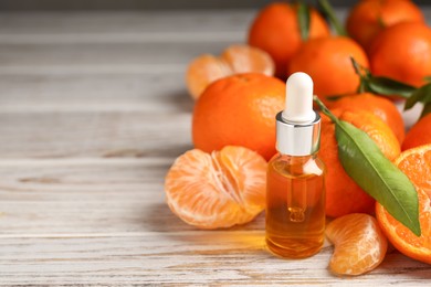 Photo of Bottle of tangerine essential oil and fresh fruits on white wooden table, closeup. Space for text