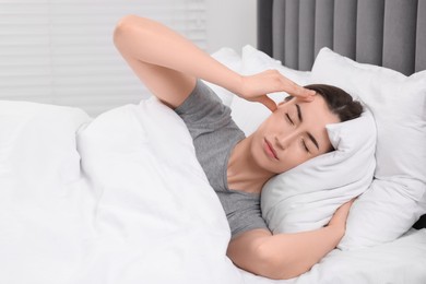 Photo of Sad woman suffering from headache in bed indoors