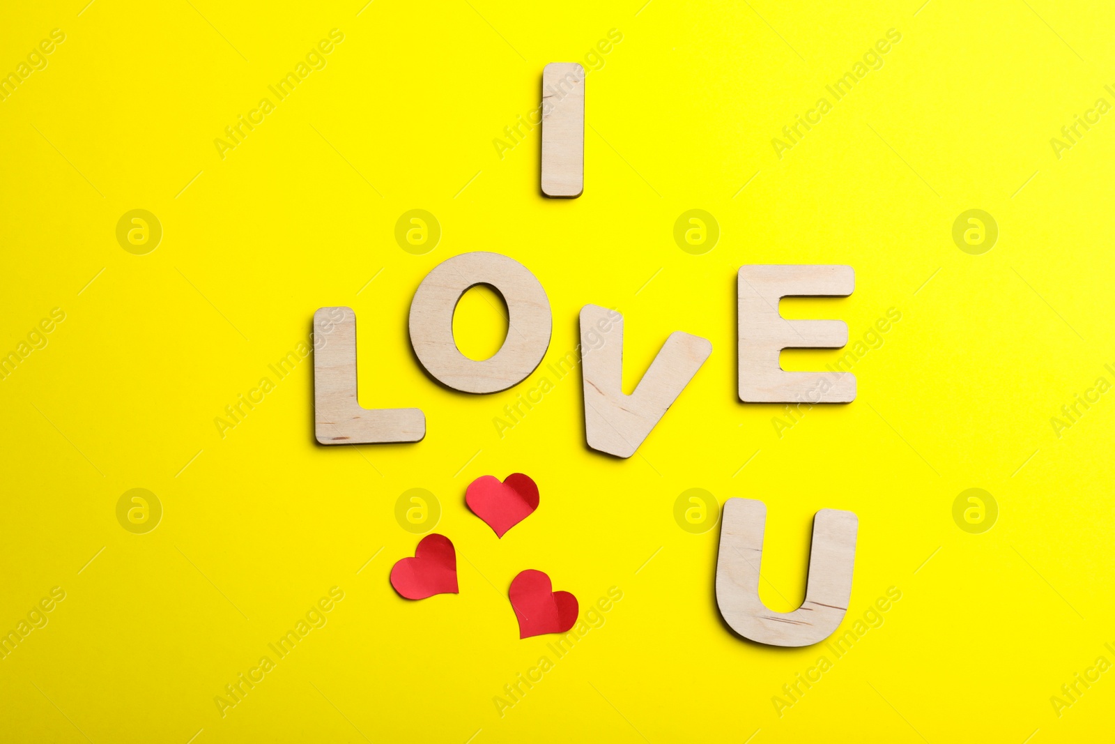 Photo of Phrase I Love You made of wooden letters on yellow background, flat lay