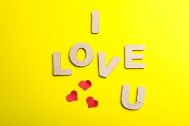 Photo of Phrase I Love You made of wooden letters on yellow background, flat lay