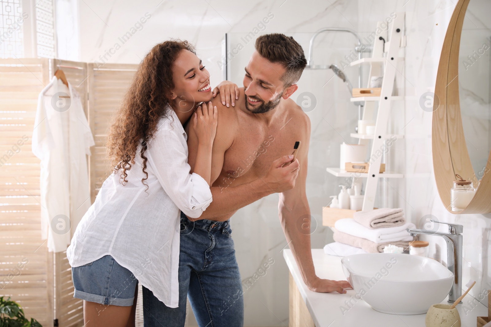 Photo of Lovely couple enjoying each other while brushing teeth in bathroom