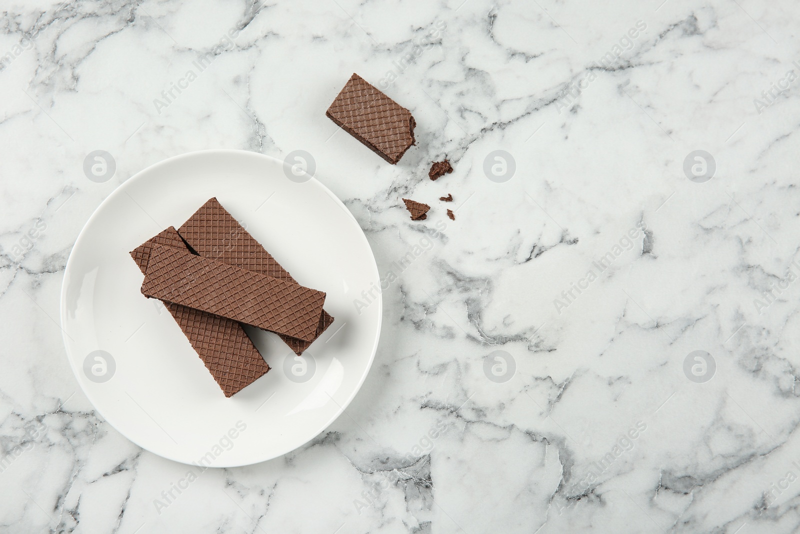 Photo of Plate of delicious chocolate wafers on marble background, top view. Space for text