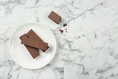 Plate of delicious chocolate wafers on marble background, top view. Space for text