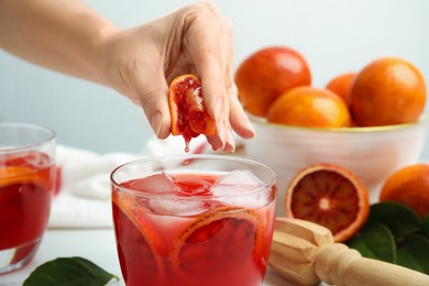 Photo of Woman squeezing sicilian orange juice into glass, closeup