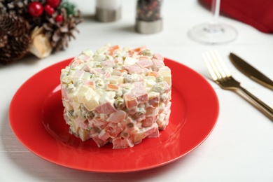 Traditional russian salad Olivier served on white wooden table