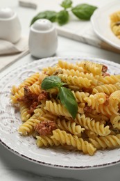 Photo of Delicious pasta with minced meat and basil served on white table, closeup