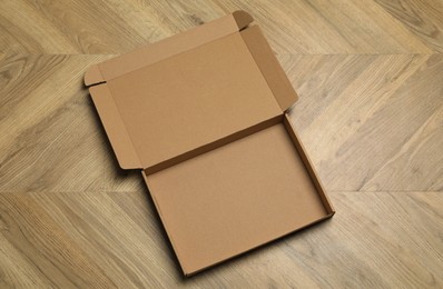 Photo of Empty open cardboard box on floor, top view