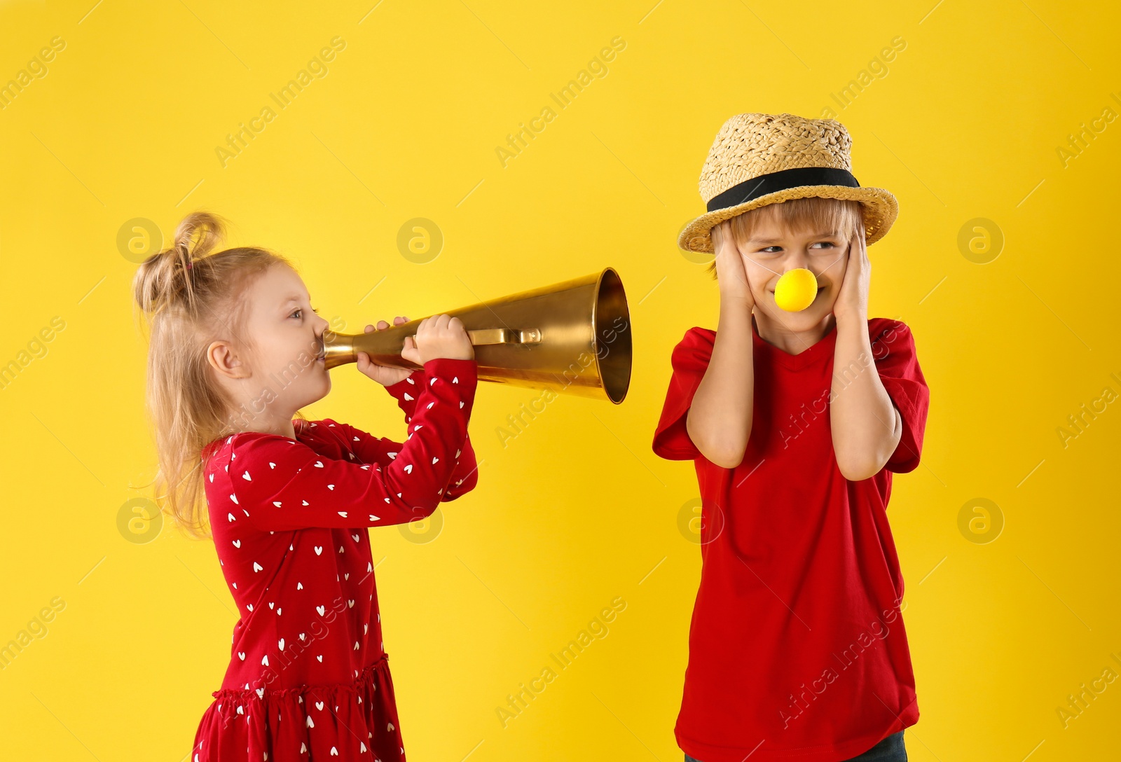 Photo of Funny kids with megaphone on yellow background. April fool's day