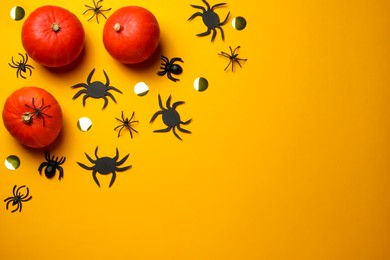 Flat lay composition with pumpkins, spiders and golden confetti on yellow background, space for text. Halloween celebration