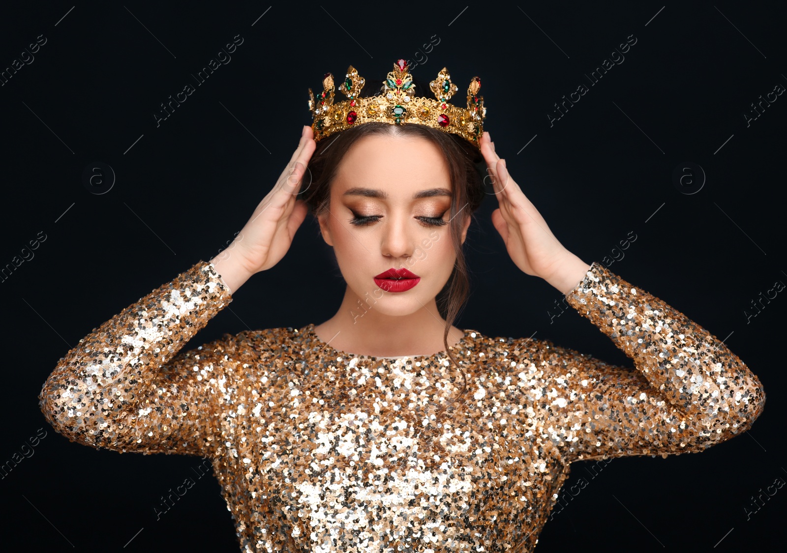 Photo of Beautiful young woman wearing luxurious crown on black background