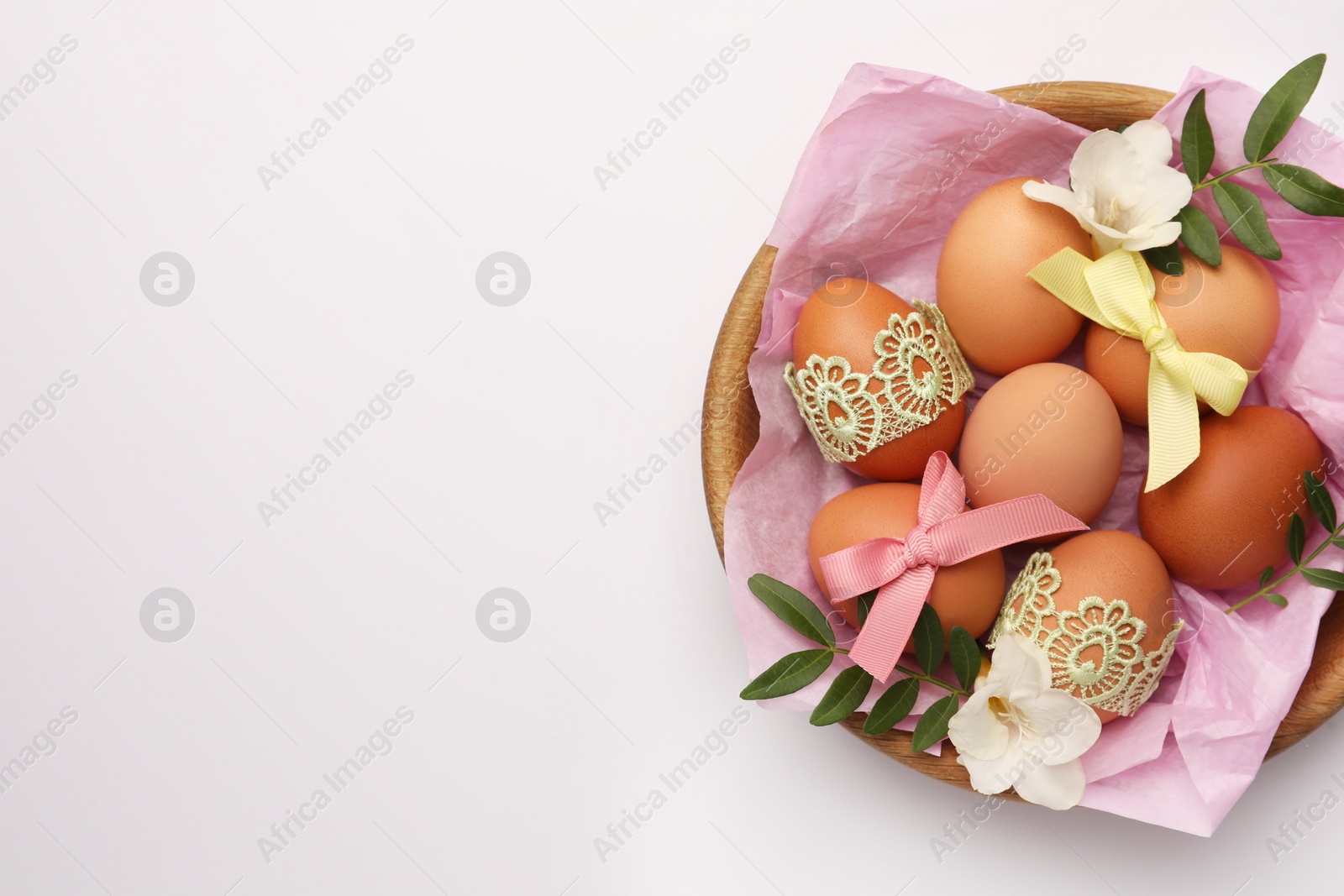 Photo of Easter eggs with colorful bows, twigs and flowers on white background, top view. Space for text