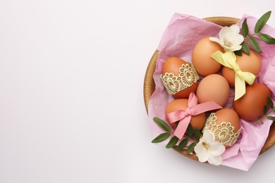 Photo of Easter eggs with colorful bows, twigs and flowers on white background, top view. Space for text