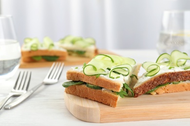 Photo of Wooden board with traditional English cucumber sandwiches on table. Space for text