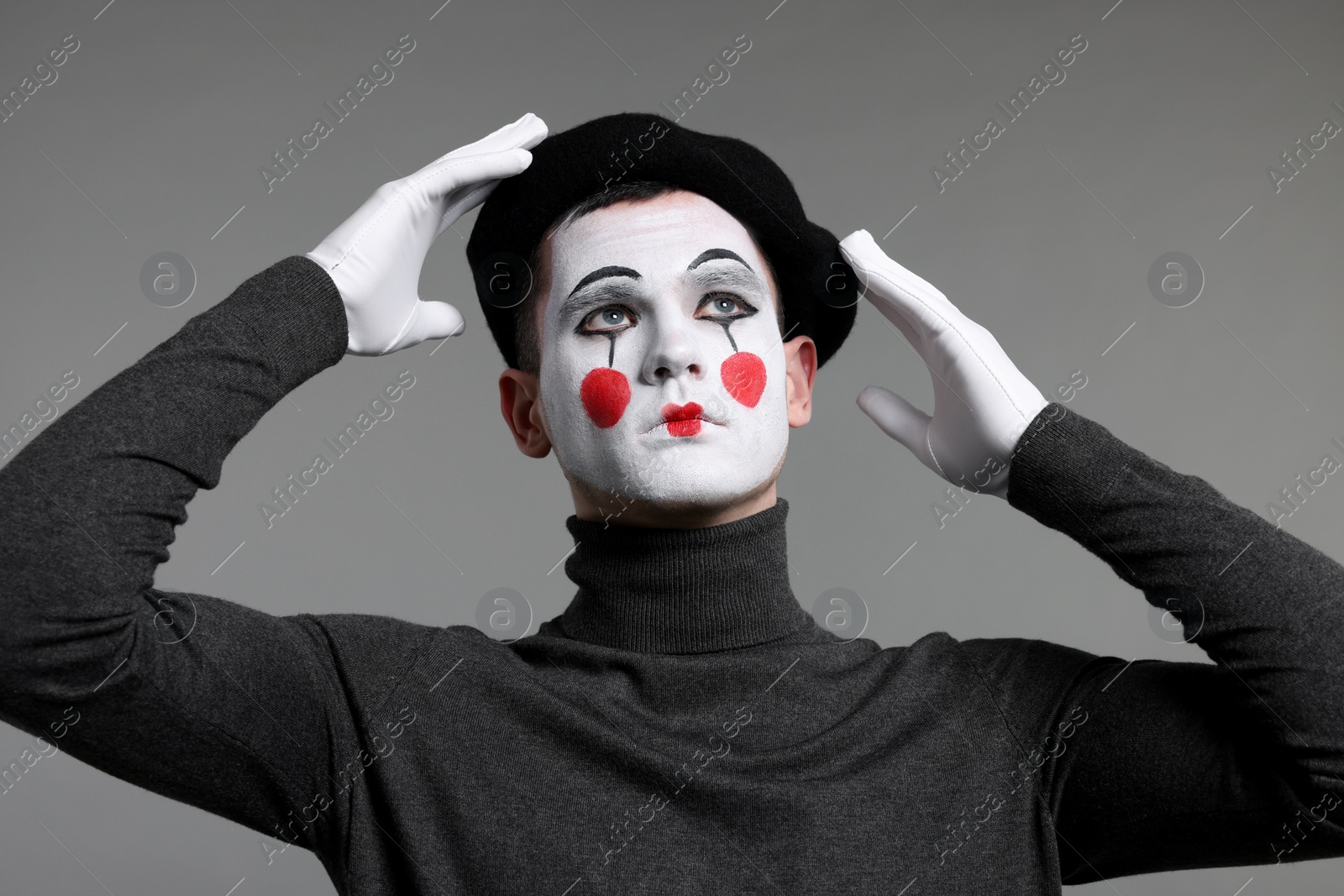 Photo of Mime artist in beret posing on grey background