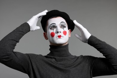 Mime artist in beret posing on grey background