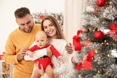 Photo of Happy family with cute baby near decorated Christmas tree at home